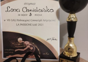 Trofea zdobyte podczas Gali Gimnastyki Artystycznej LA PASSIONE Łódź 2021 – dyplom, medal i puchar.